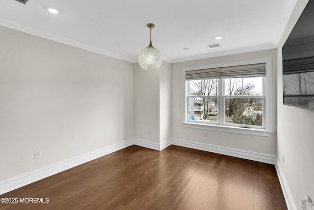 spare room featuring dark wood-style floors, visible vents, baseboards, and ornamental molding