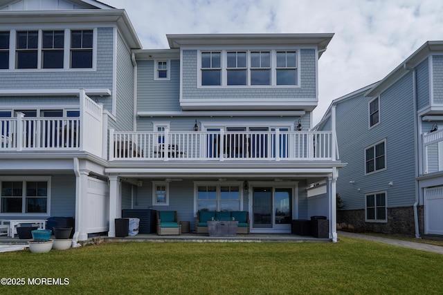 back of property featuring a patio area, a balcony, a lawn, and board and batten siding