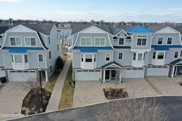 shingle-style home with a residential view, a gambrel roof, metal roof, driveway, and a standing seam roof