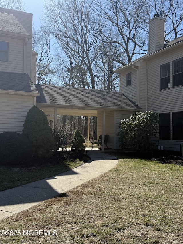 exterior space with a yard and roof with shingles