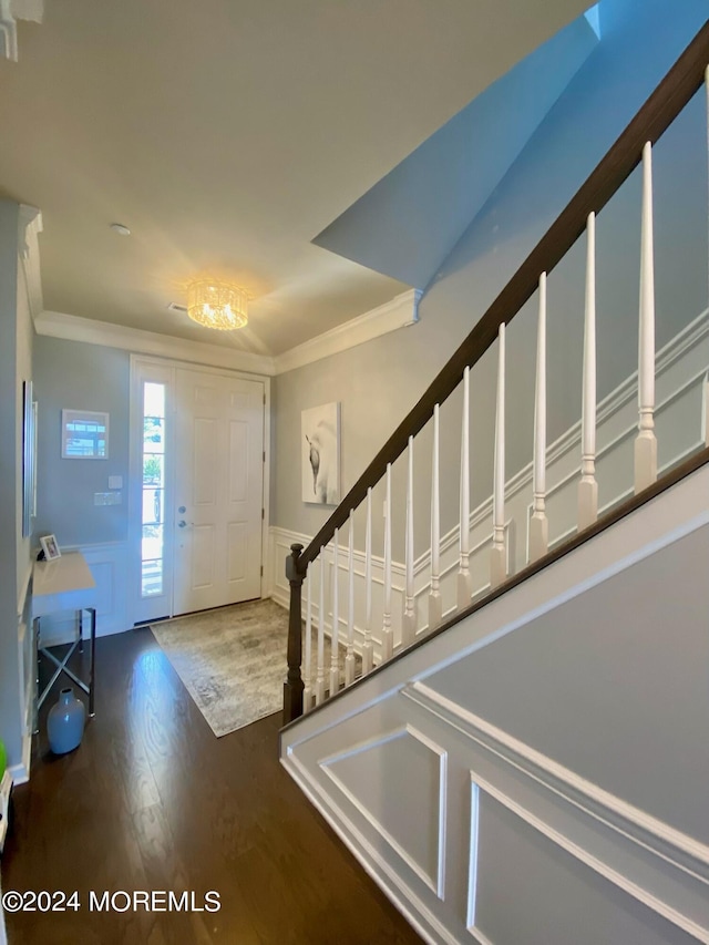 entrance foyer featuring crown molding, a wainscoted wall, stairs, wood finished floors, and a decorative wall