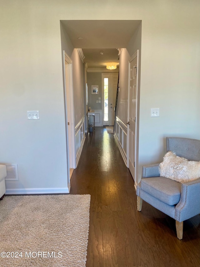 hallway with dark wood finished floors, visible vents, and baseboards