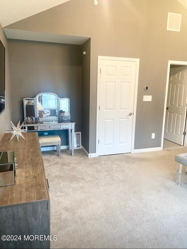 carpeted office space with visible vents, high vaulted ceiling, and baseboards