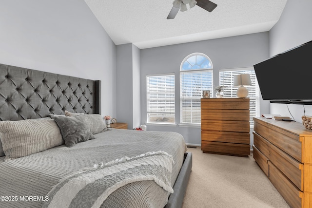 bedroom with light colored carpet, a textured ceiling, and a ceiling fan