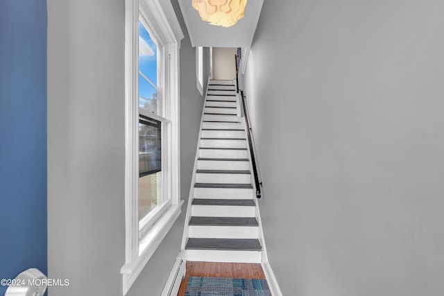 stairway featuring baseboards, plenty of natural light, and wood finished floors