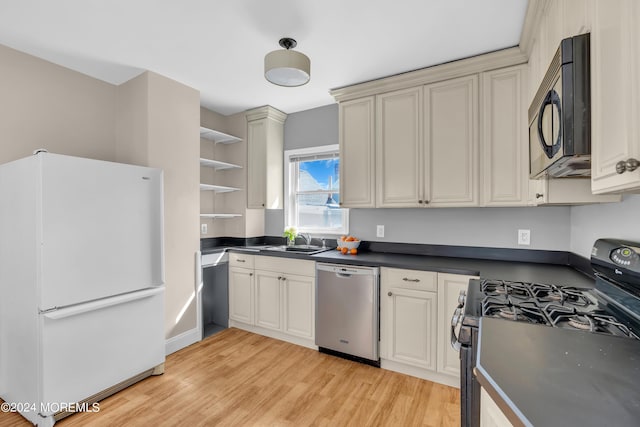 kitchen featuring black microwave, range with gas stovetop, stainless steel dishwasher, freestanding refrigerator, and open shelves