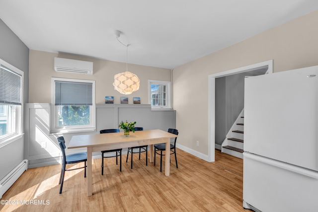 dining room with a wall mounted AC, stairway, light wood finished floors, a baseboard radiator, and a healthy amount of sunlight