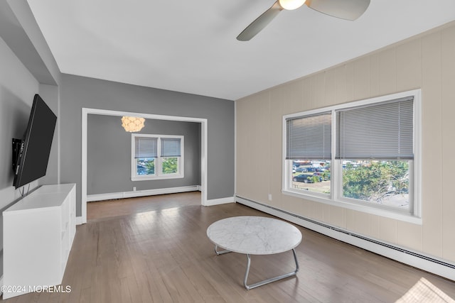 unfurnished living room featuring plenty of natural light, baseboard heating, and hardwood / wood-style floors