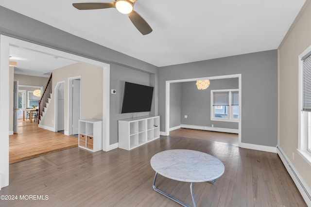 living room with a baseboard heating unit, hardwood / wood-style flooring, and stairs