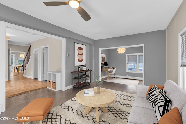 living area featuring a baseboard heating unit, stairway, wood finished floors, and baseboards