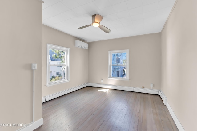 spare room featuring a wealth of natural light, hardwood / wood-style floors, a wall mounted AC, and a baseboard radiator