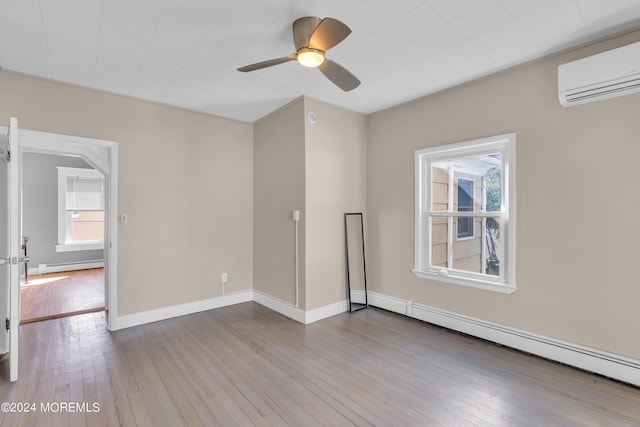 empty room featuring a wall unit AC, hardwood / wood-style flooring, and a baseboard radiator