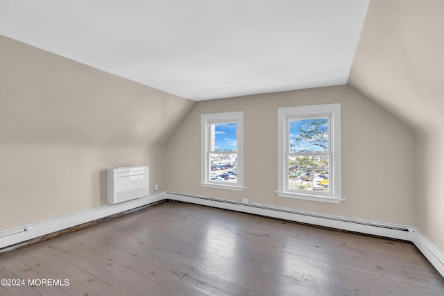 additional living space with vaulted ceiling, baseboard heating, wood-type flooring, and a baseboard radiator