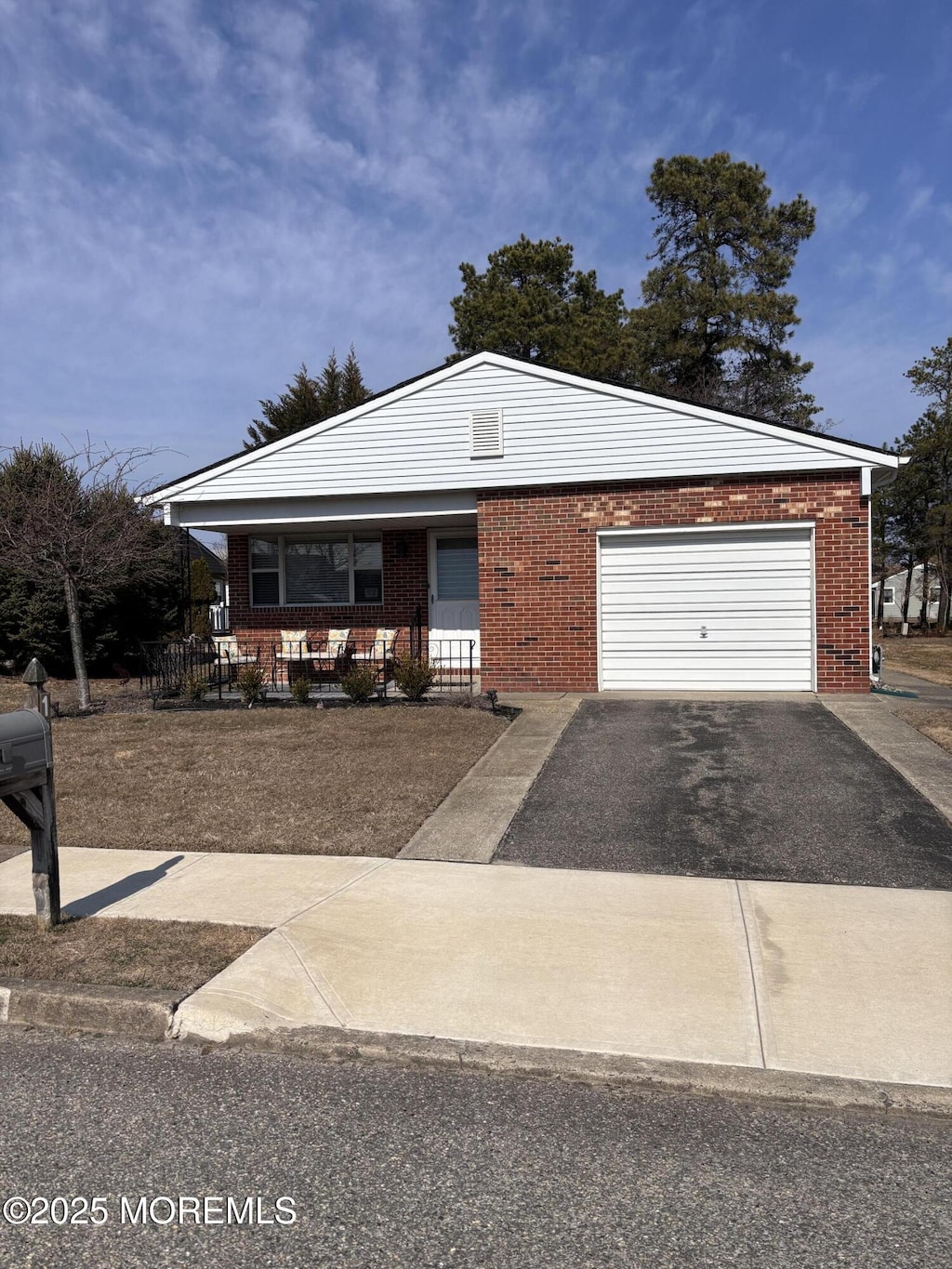 view of front of home with a garage, brick siding, a porch, and aphalt driveway