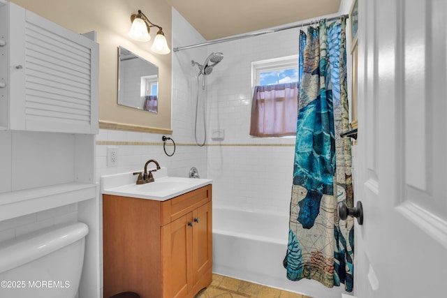 bathroom with a wainscoted wall, toilet, shower / bath combo, tile walls, and vanity