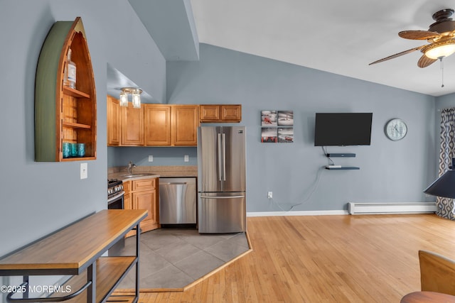 kitchen with a ceiling fan, a sink, stainless steel appliances, a baseboard heating unit, and light wood-type flooring