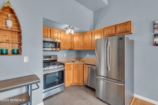 kitchen featuring baseboards, light countertops, light tile patterned floors, appliances with stainless steel finishes, and a sink