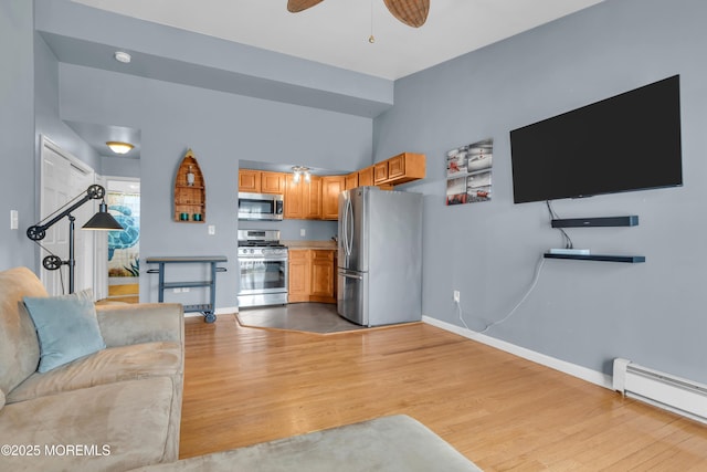 living area with baseboards, a ceiling fan, light wood-type flooring, and a baseboard radiator