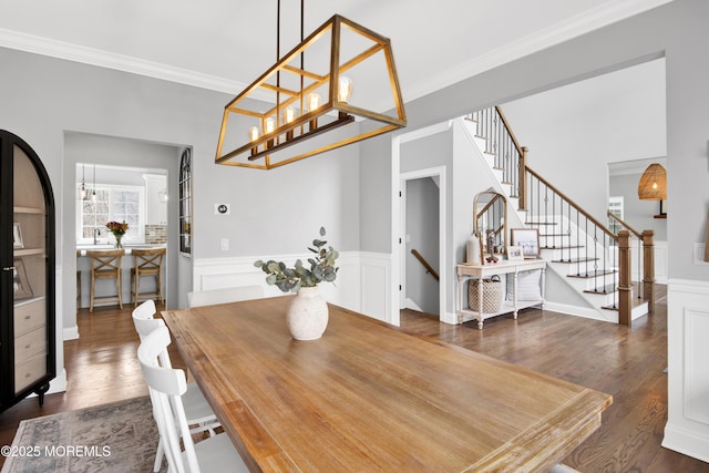 dining room featuring a wainscoted wall, stairway, crown molding, and dark wood-type flooring