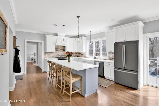 kitchen with a breakfast bar, ornamental molding, a center island, freestanding refrigerator, and dishwasher