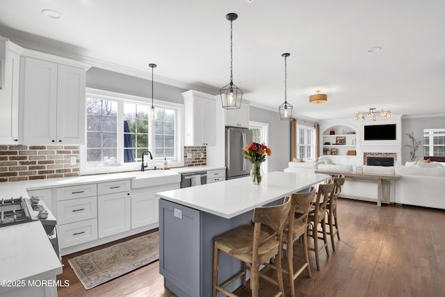 kitchen featuring dark wood finished floors, stainless steel appliances, crown molding, and a sink