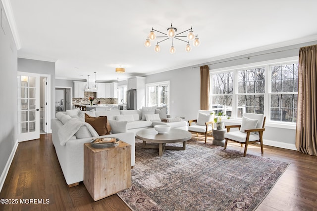 living room featuring dark wood-type flooring, a notable chandelier, crown molding, and baseboards