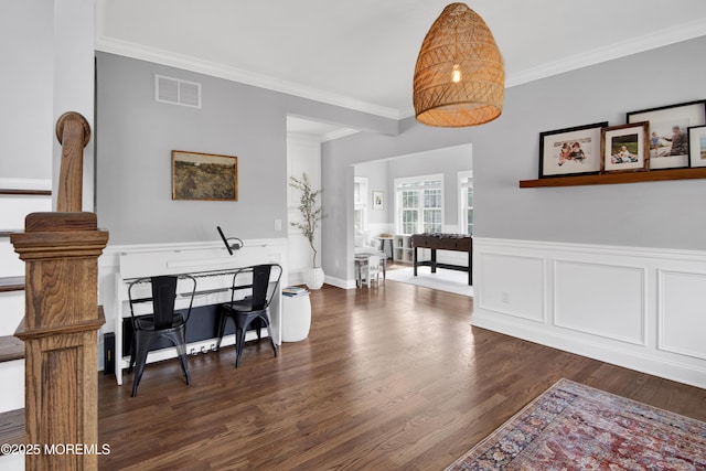 dining area featuring visible vents, wainscoting, wood finished floors, and ornamental molding