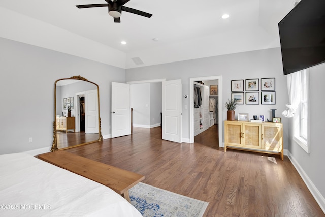 bedroom with recessed lighting, a walk in closet, baseboards, and wood finished floors