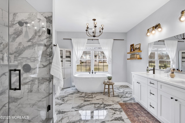 full bathroom with a marble finish shower, double vanity, a freestanding tub, a notable chandelier, and marble finish floor