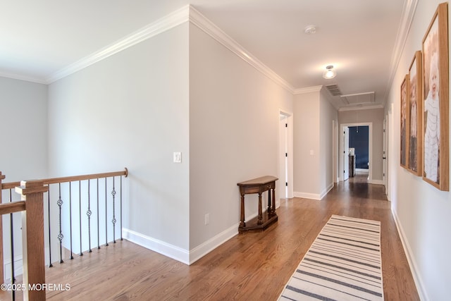 hall featuring baseboards, attic access, wood finished floors, and crown molding