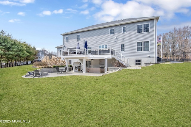 back of property with a lawn, fence, stairway, a wooden deck, and a patio area