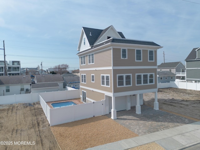 view of home's exterior with decorative driveway, a garage, board and batten siding, and a fenced backyard