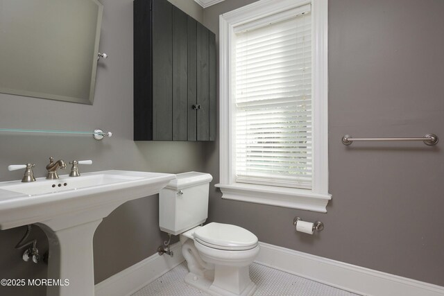 bathroom with a sink, baseboards, tile patterned floors, and toilet