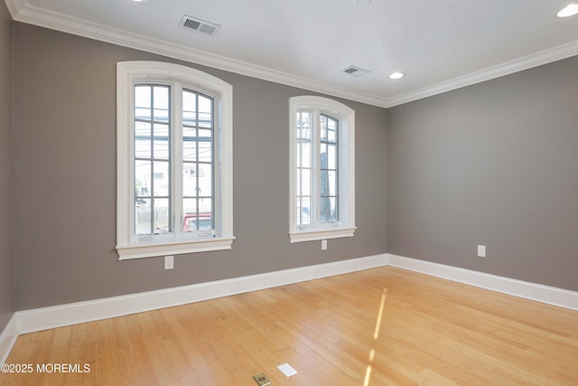 spare room with baseboards, visible vents, ornamental molding, and light wood-type flooring