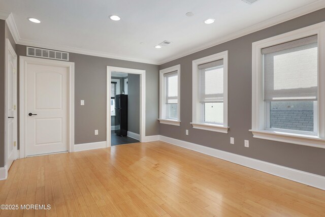 unfurnished bedroom featuring baseboards, ornamental molding, light wood-type flooring, and visible vents