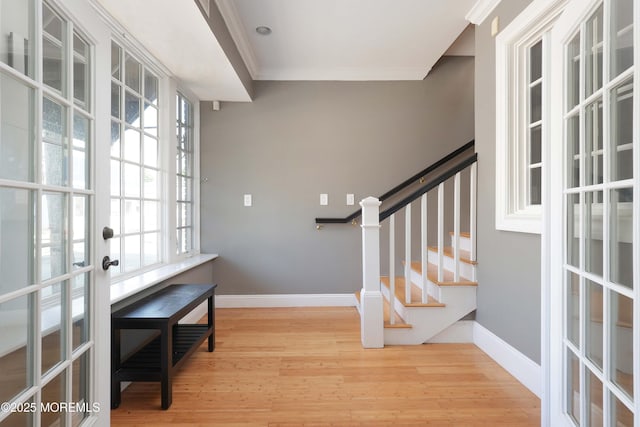 foyer entrance with french doors, wood finished floors, ornamental molding, and stairway