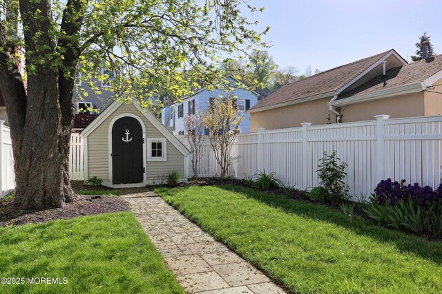 view of yard with a storage shed, fence, and an outbuilding