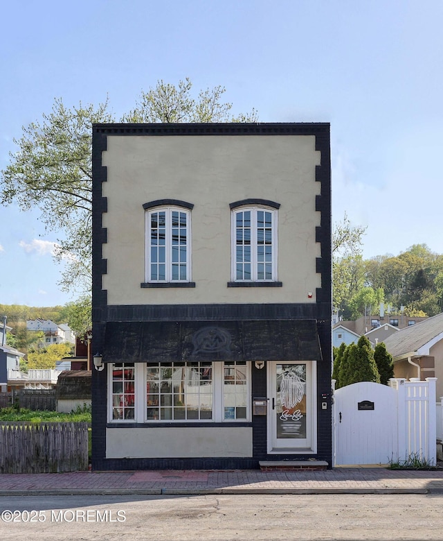 view of front facade featuring a gate, stucco siding, and fence