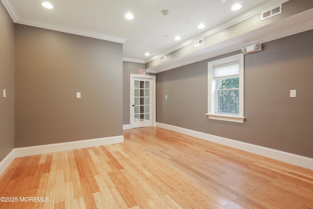 empty room featuring baseboards, visible vents, ornamental molding, and light wood finished floors