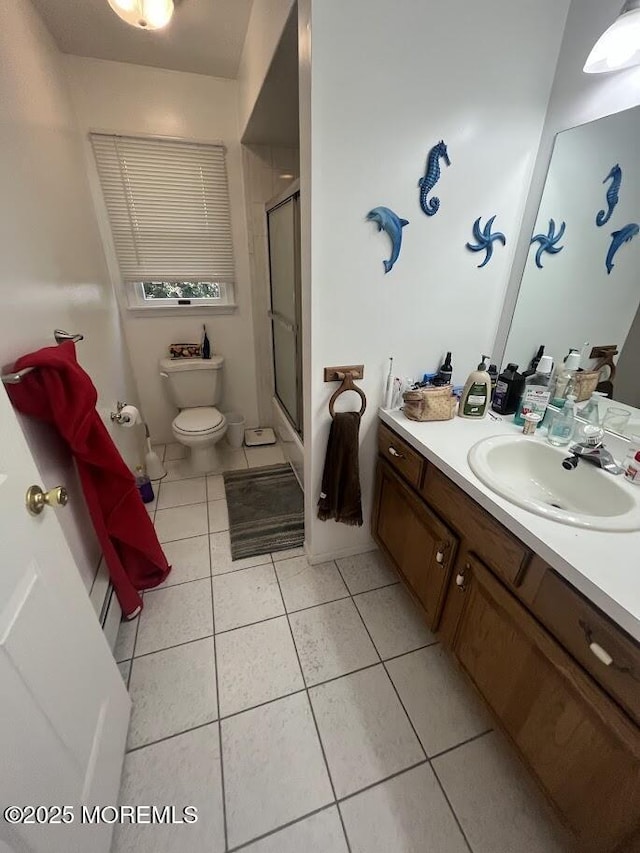 bathroom featuring tile patterned flooring, a shower stall, toilet, and vanity