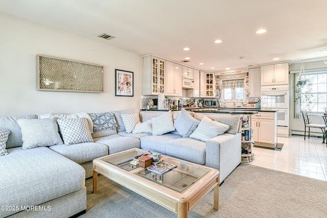 living room with visible vents, recessed lighting, light tile patterned floors, a baseboard radiator, and light colored carpet