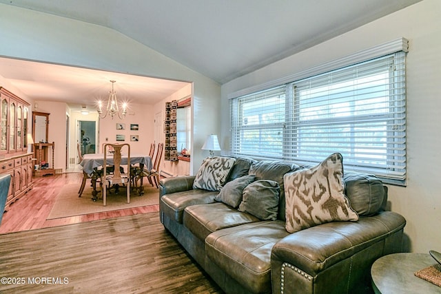 living area featuring lofted ceiling, wood finished floors, a wealth of natural light, and a chandelier