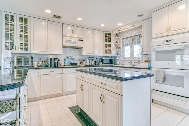 kitchen with tasteful backsplash, white appliances, light tile patterned floors, and visible vents