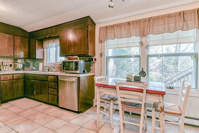 kitchen with tile countertops, vaulted ceiling, light tile patterned floors, appliances with stainless steel finishes, and a sink