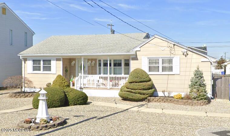 view of front of property featuring roof with shingles, a porch, and fence