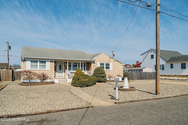 view of front of property featuring a porch, fence, and roof with shingles