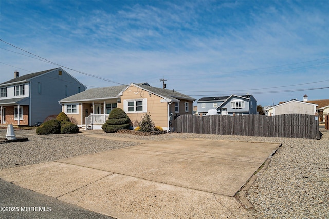 view of front of property with a porch, a shingled roof, and fence