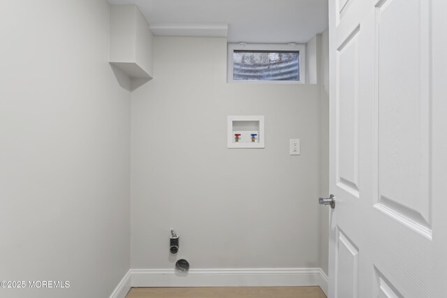 clothes washing area featuring baseboards, washer hookup, laundry area, and light wood finished floors