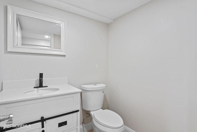 half bath featuring vanity, toilet, and baseboards