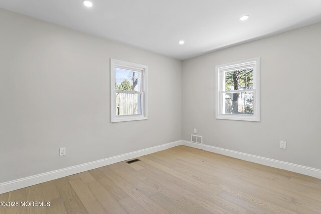 empty room featuring visible vents, light wood-style flooring, and baseboards